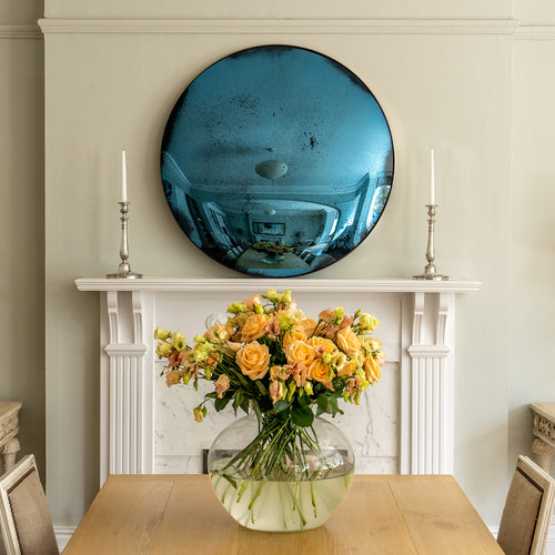 Aged Blue Convex Round Mirror placed on a white mantlepiece and flanked by candles