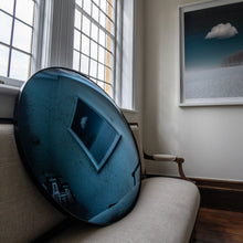 Load image into Gallery viewer, Aged Blue Round Convex Mirror placed on a cream linen sofa and reflecting a painting of clouds