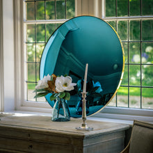 Load image into Gallery viewer, A Blue Round Convex Mirror propped on a wooden sideboard and against a large bay window. A vase of flowers and candle stick is placed in front of the mirror.
